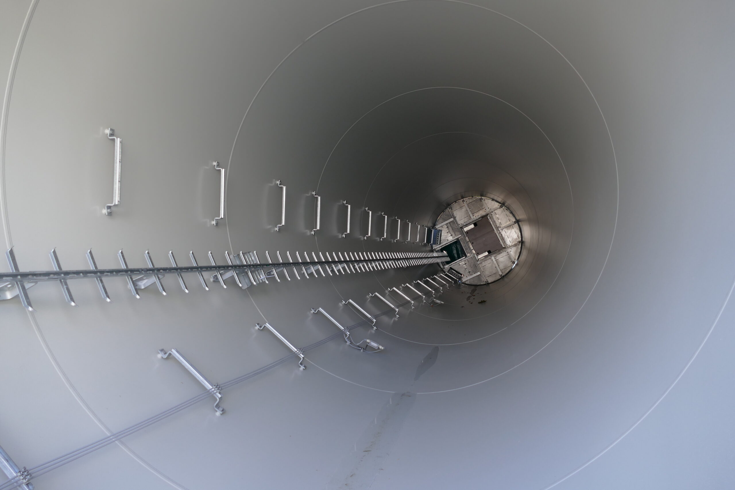 The inside of an under-construction wind turbine’s hollow vertical column, showing the built-in ladder rungs that allow access to the nacelle (top part) for maintenance and repair purposes