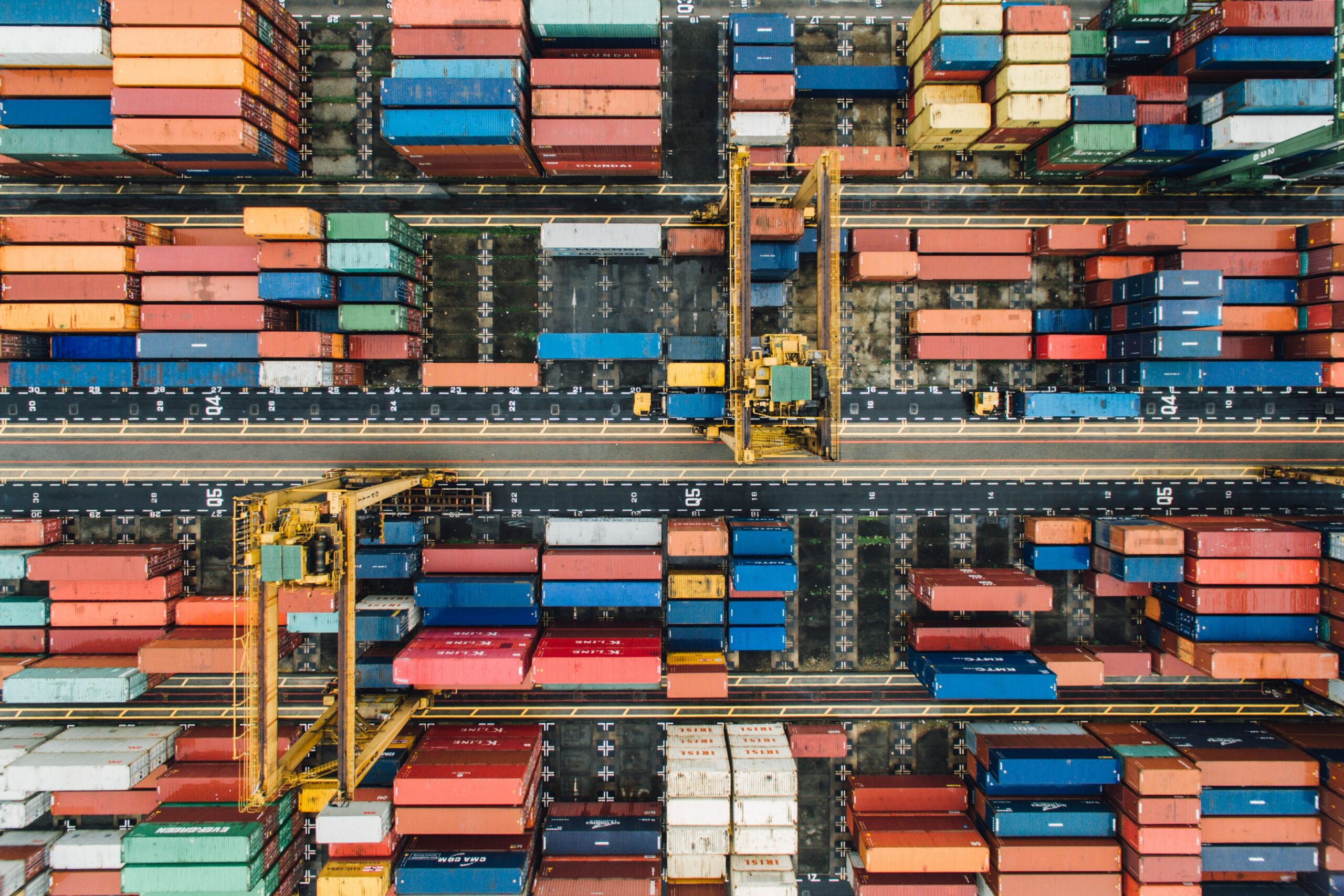Aerial shot of many shipping containers of different sizes and colours standing in a depot/shipping yard