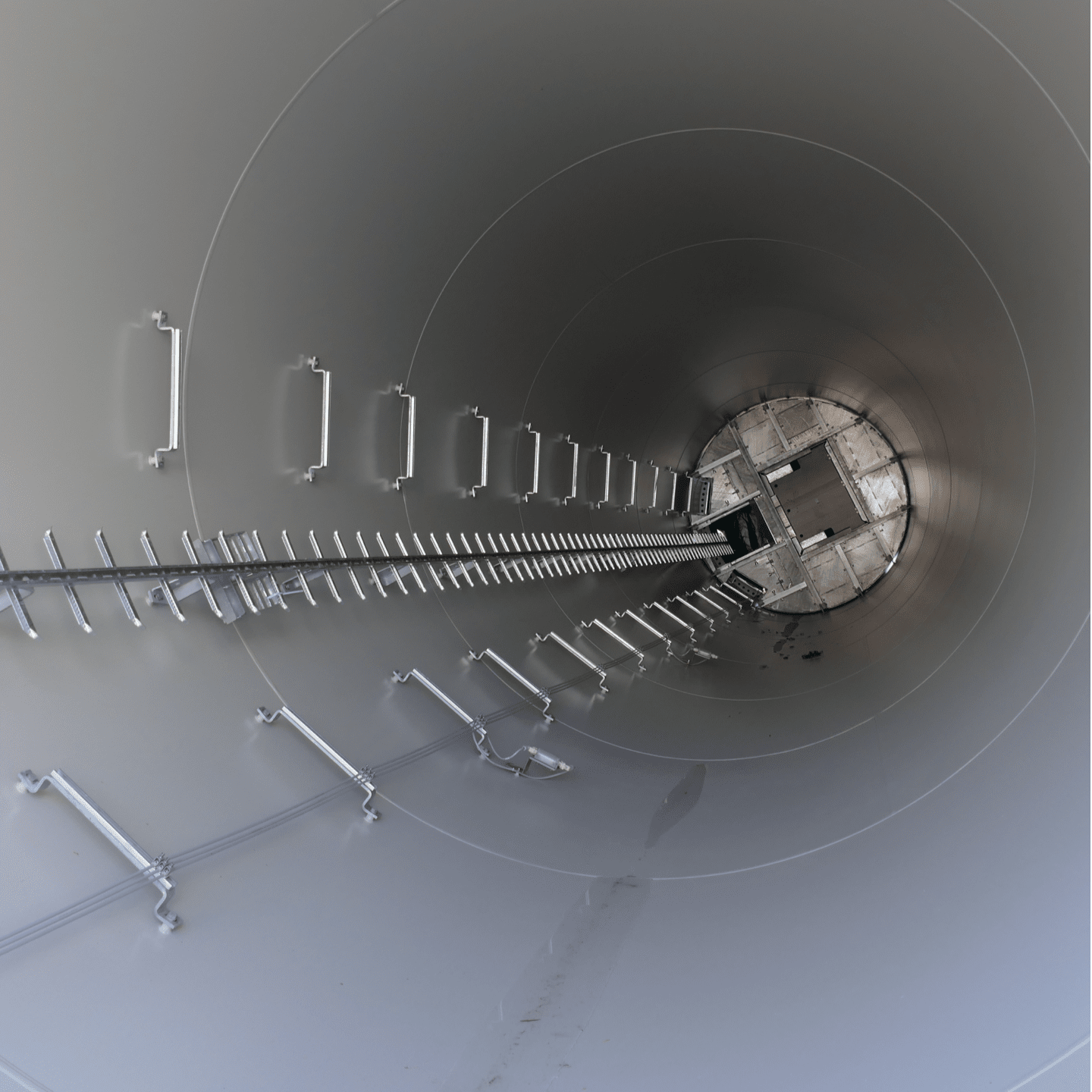 The inside of an under-construction wind turbine’s hollow vertical column, showing the built-in ladder rungs that allow access to the nacelle (top part) for maintenance and repair purposes