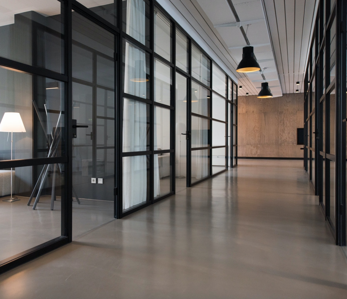 A corridor in a modern office building, with glassed walls on either side,