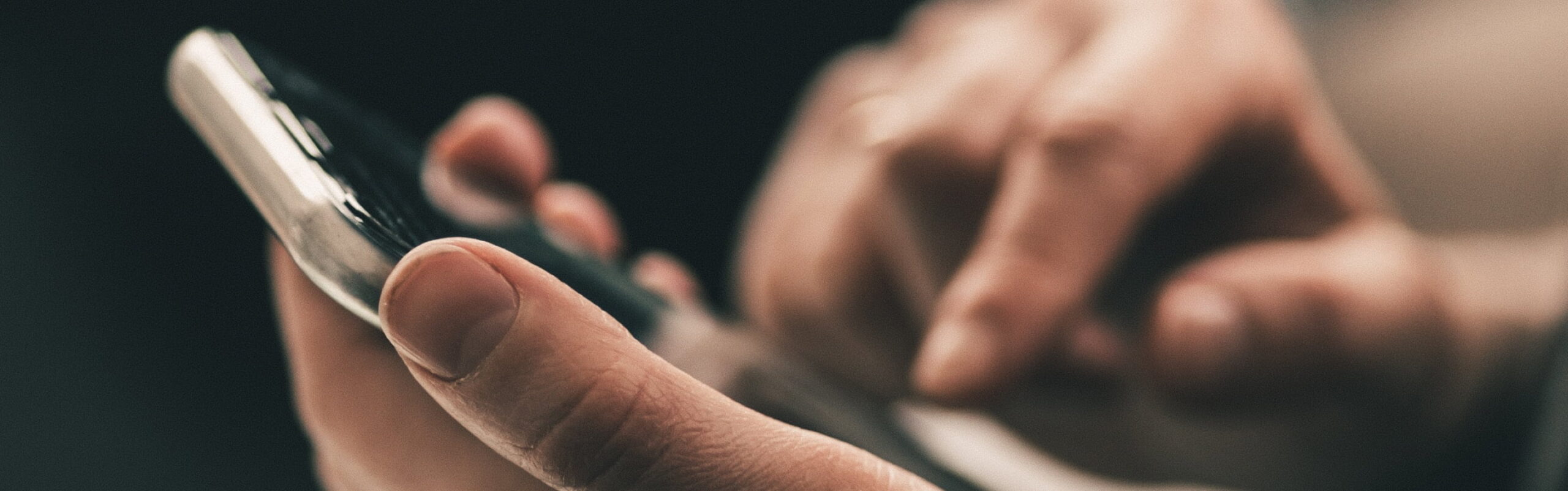 A hand holding a large-screen, modern smartphone, shot from the side