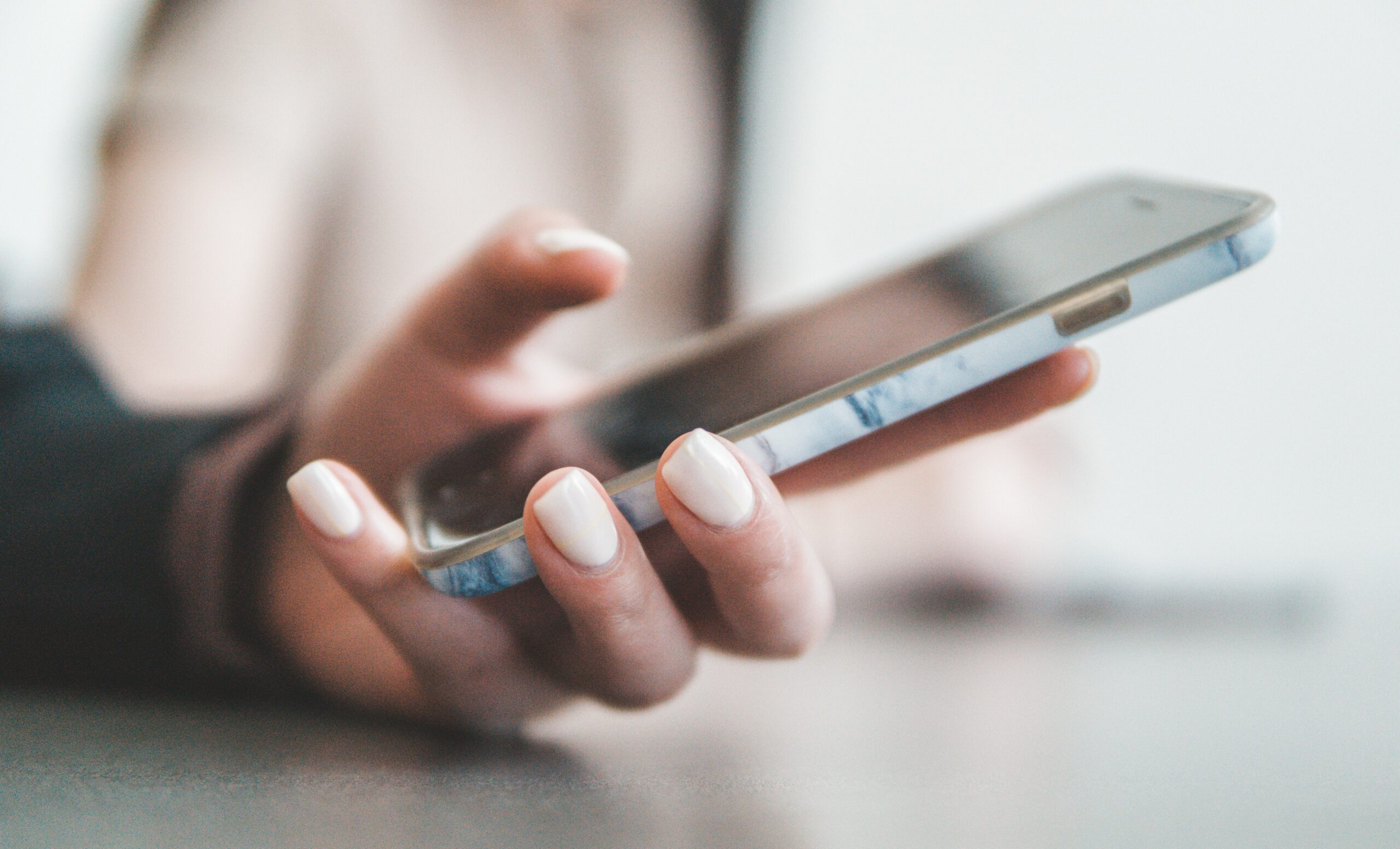 A hand holding a large-screen, modern smartphone, shot from the side